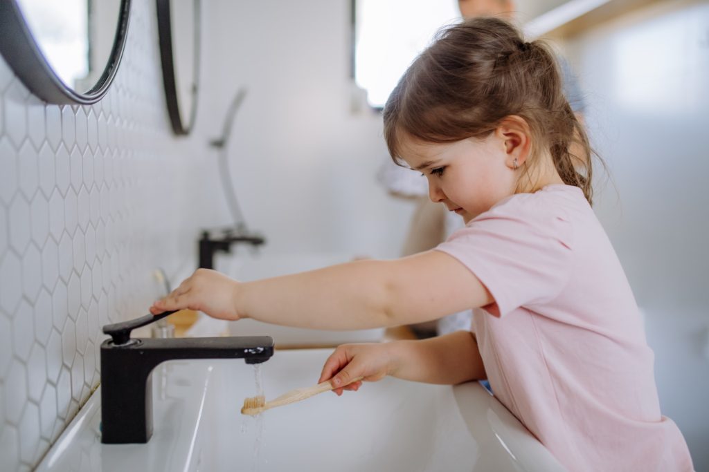 girl washing hands in bathroom faucet